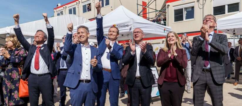 Wichtige Vertreter aus Politik und Wirtschaft jubeln beim Stapelfest an der Landsberger Allee in Berlin, nachdem das letzte Modul erfolgreich platziert wurde.