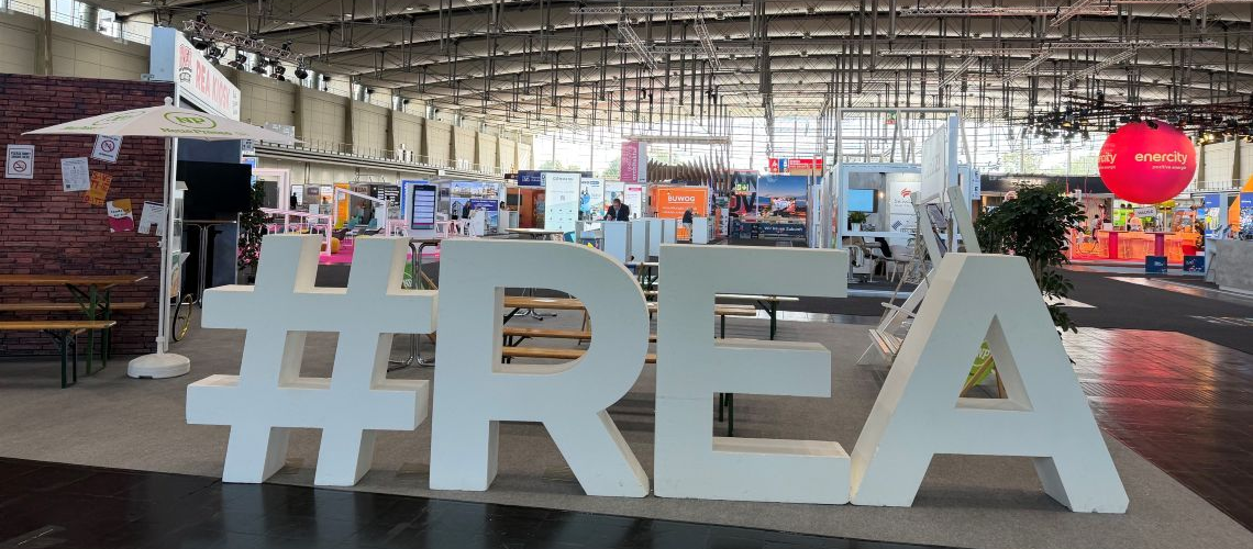 Leuchtende „REA 2026“ Schrift in einer Messehalle der Real Estate Arena